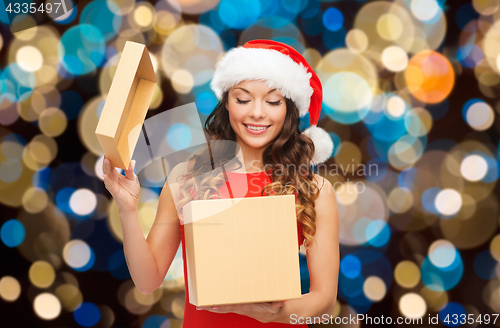 Image of smiling woman in santa hat opening christmas gift