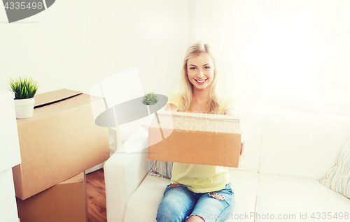 Image of smiling young woman with cardboard box at home