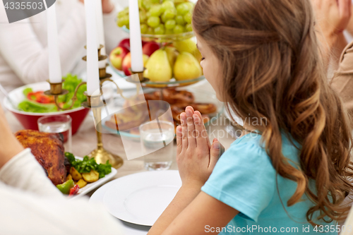 Image of girl with family having dinner and praying at home