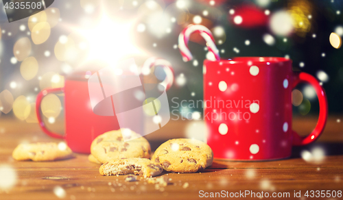 Image of christmas candy canes and cups on wooden table