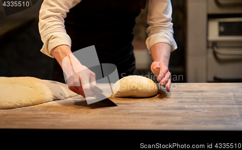 Image of baker portioning dough with bench cutter at bakery