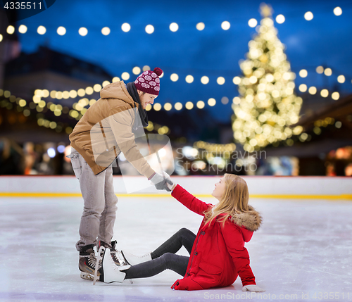 Image of man helping woman on christmas skating rink