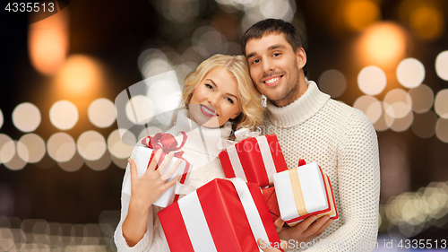 Image of happy couple in sweaters holding christmas gifts