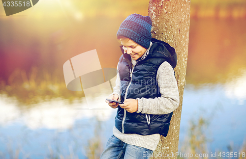 Image of happy boy playing game on smartphone outdoors