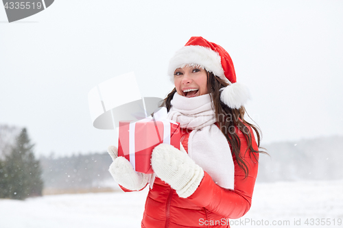 Image of happy woman in santa hat with chrismas gift