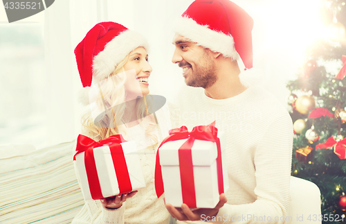 Image of happy couple at home exchanging christmas gifts