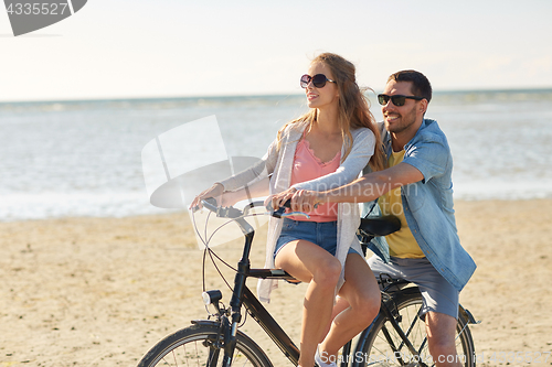 Image of happy young couple riding bicycle on beach