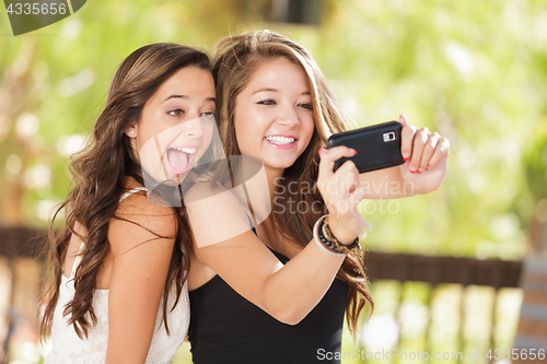 Image of Two Attractive Mixed Race Girlfriends Using Their Smart Cell Pho