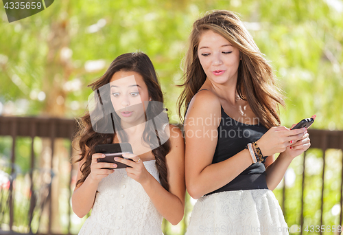 Image of Two Expressive Mixed Race Girlfriends Using Their Smart Cell Pho