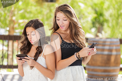 Image of Two Expressive Mixed Race Girlfriends Using Their Smart Cell Pho