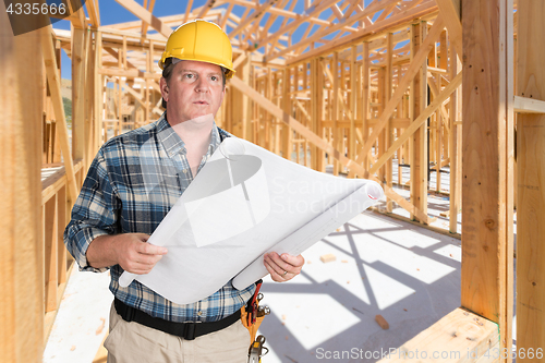 Image of Male Contractor With House Plans Wearing Hard Hat Inside New Hou