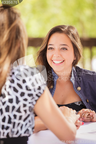 Image of Two Mixed Race Girlfriends Having A Conversation At An Outoor Pa