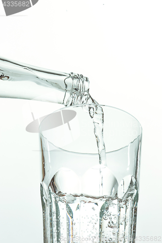 Image of Pouring water from bottle into glass on white