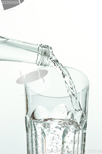 Image of Pouring water from bottle into glass on white