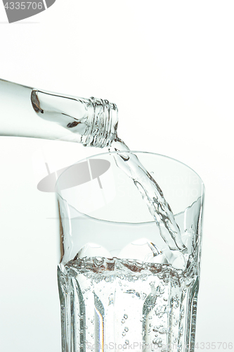 Image of Pouring water from bottle into glass on white