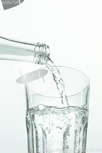 Image of Pouring water from bottle into glass on white