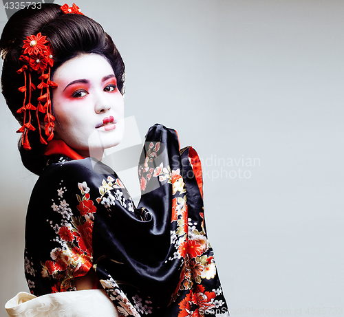 Image of young pretty geisha in kimono with sakura and red decoration des