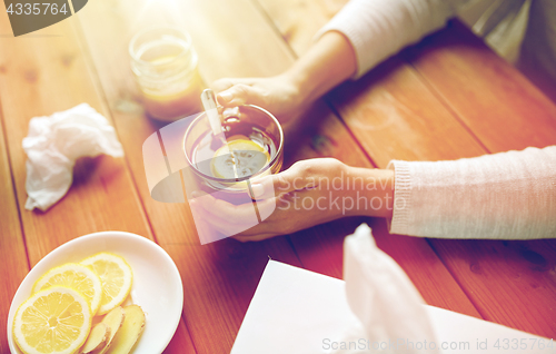 Image of ill woman drinking tea with lemon and ginger