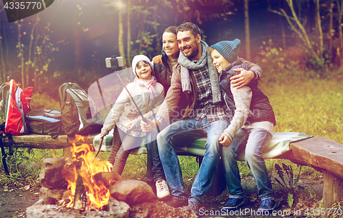 Image of family with smartphone taking selfie near campfire