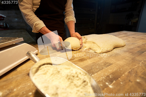 Image of baker portioning dough with bench cutter at bakery