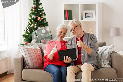 Image of happy senior couple with tablet pc at christmas