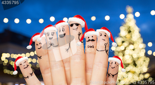 Image of fingers in santa hats over night lights background