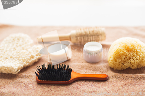 Image of hair brush, cream, sponge, soap bar and bath towel