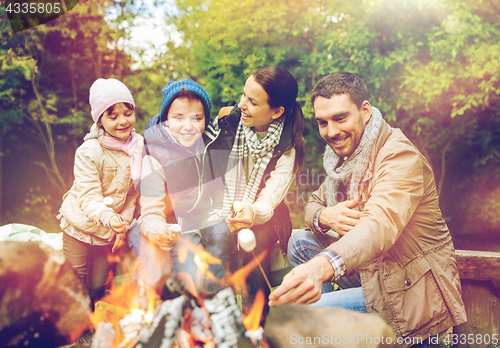 Image of happy family roasting marshmallow over campfire