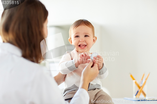 Image of happy doctor or pediatrician with baby at clinic