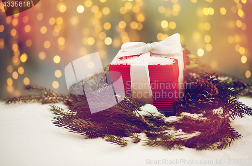 Image of christmas gift and fir wreath with cones on snow