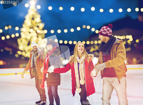 Image of happy friends at christmas skating rink