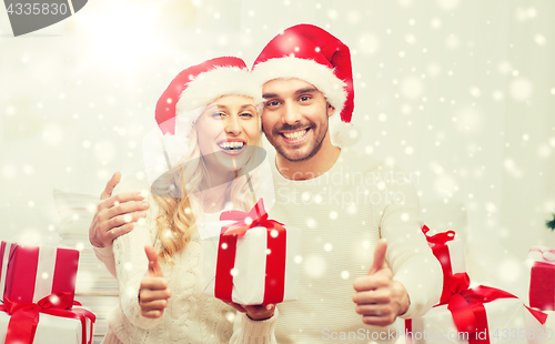 Image of happy couple with christmas gifts and thumbs up