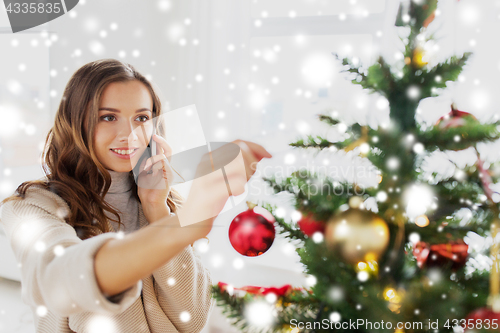 Image of woman with smartphone decorating christmas tree