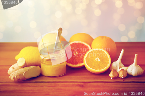 Image of honey, citrus fruits, ginger and garlic on wood