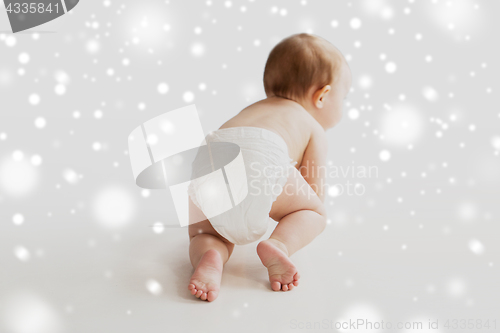 Image of little baby in diaper crawling on white floor