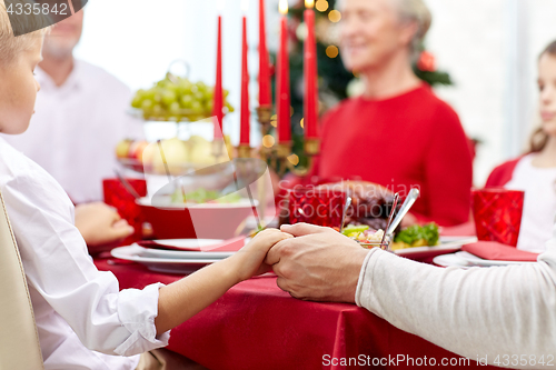 Image of family having holiday dinner and praying at home