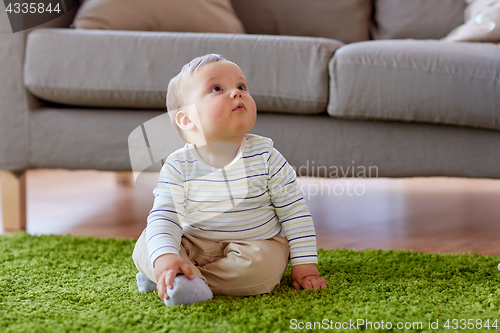 Image of baby boy sitting on floor at home