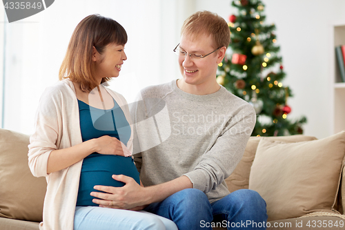 Image of pregnant wife with husband at home at christmas