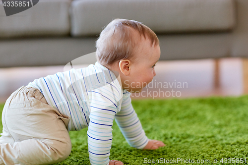 Image of baby boy crawling on floor at home