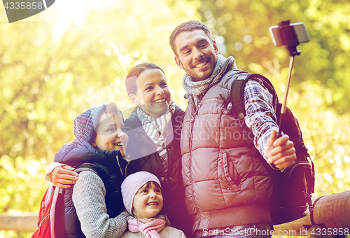 Image of happy family with smartphone selfie stick at camp