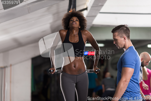 Image of black woman doing parallel bars Exercise with trainer