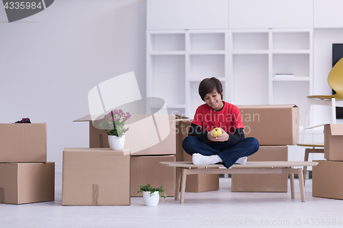 Image of boy sitting on the table with cardboard boxes around him