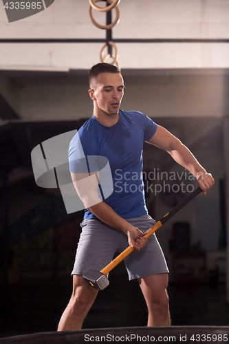 Image of man workout with hammer and tractor tire