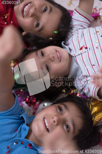 Image of kids  blowing confetti while lying on the floor