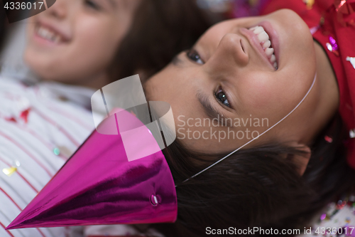 Image of kids  blowing confetti while lying on the floor