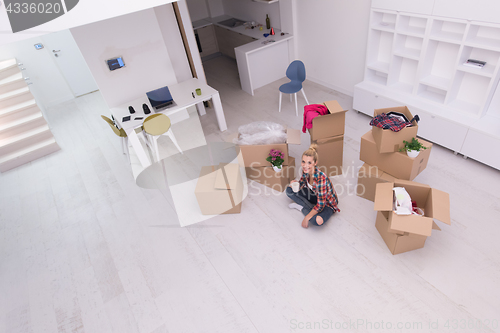 Image of woman with many cardboard boxes sitting on floor