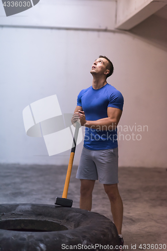 Image of man workout with hammer and tractor tire