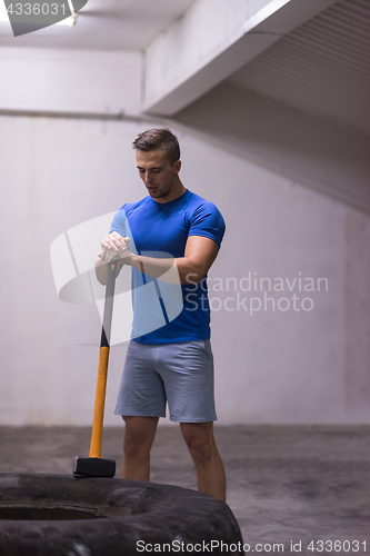 Image of man workout with hammer and tractor tire