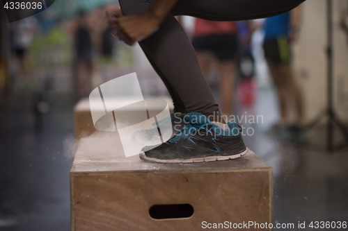 Image of black woman is performing box jumps at gym