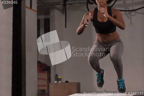 Image of black woman is performing box jumps at gym